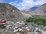 101 Marpha View Towards North After lunch in Jomsom, it took us only an hour to trek along the river bank much of the way to Marpha. Marpha (2680m) is situated in a little in a side valley and is protected from the strong winds, which blow in the middle of the river valley. The rooftops are bordered by neat stacks of firewood and provide a place where the women can work in the sun, drying and processing their produce. Everything in Marpha is clean and neat.